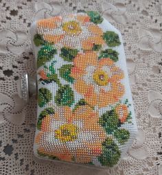 a small case with flowers on it sitting on a lace doily covered tablecloth