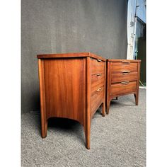 two wooden dressers sitting next to each other on carpeted floor in front of wall