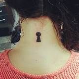 a woman's neck with a small key tattoo on the back of her neck