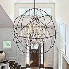 a chandelier hanging from the ceiling in a room with white walls and wood floors