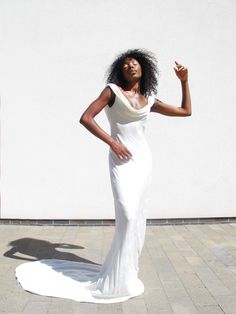 a woman in a white dress posing for the camera with her hand on her hip