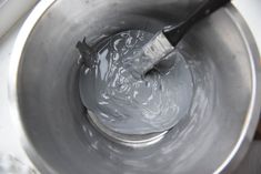 a metal mixing bowl filled with liquid and a brush