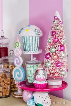 a table topped with lots of cupcakes next to a christmas tree and candy