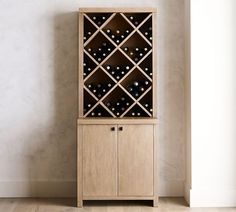 a wooden cabinet with wine bottles in it next to a white wall and hardwood floor