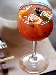 a glass filled with fruit and ice sitting on top of a table