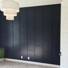 an empty room with black paneling on the wall and a plant next to it