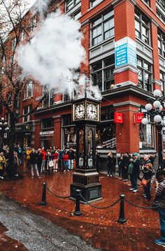 people are standing outside in front of a building with steam coming out of the top