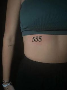 a woman's stomach with the number 555 tattooed on her lower side belly