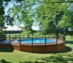 an above ground pool surrounded by wooden decks and fenced in area with green grass