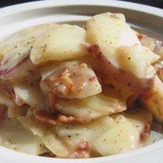 a white bowl filled with potatoes and meat