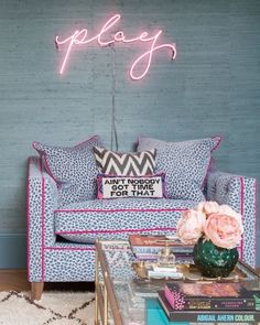 a living room filled with furniture and a neon sign on the wall above it's headboard