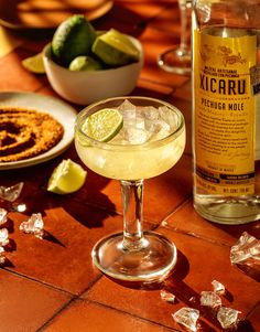 a margarita cocktail sitting on top of a table next to a bowl of chips and a bottle