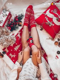 two people laying on top of a bed covered in blankets and christmas decorations next to each other