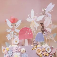 there is a cake decorated with flowers and fairy figurines