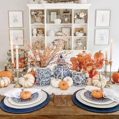 the table is set with pumpkins and blue dishes