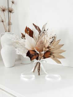 an arrangement of dried flowers on a white table