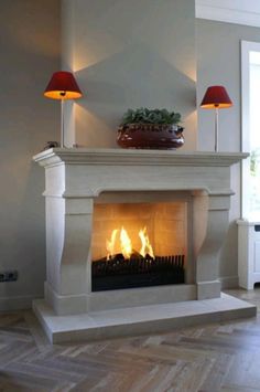 a white fireplace with two red lamps on top