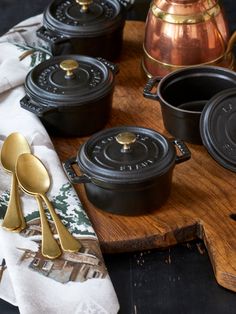 a wooden tray topped with black pots and pans