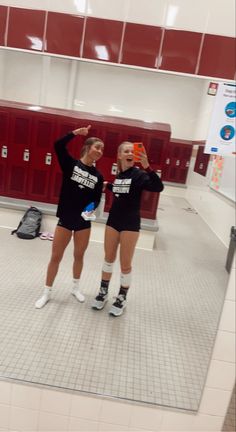 two girls in black shirts and white socks posing for the camera with their hands up