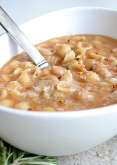 a bowl of macaroni and cheese soup with a ladle in the bowl