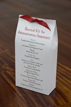 a small white box with a red ribbon on it sitting on top of a wooden table