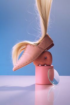 a doll with blonde hair sitting on top of a pink object