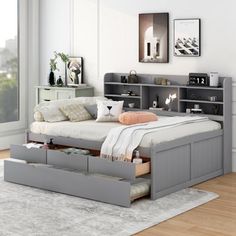 a bedroom with a bed, bookcases and an open drawer under the bed