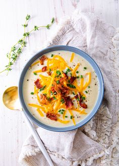 a bowl of soup with bacon, cheese and chives