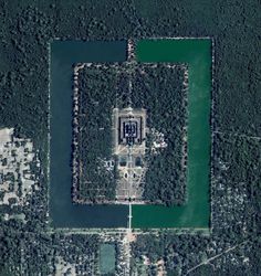 an aerial view of a large building in the middle of some water and land with trees around it