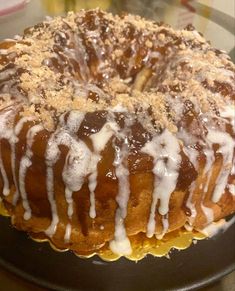 a bundt cake covered in icing and crumbs on a black plate