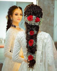 a woman with long hair and flowers in her hair is looking at herself in the mirror