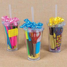 three plastic cups filled with different types of pens and pencils on top of a table