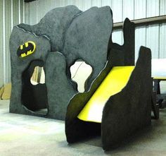 an indoor play area for children with batman theme and yellow slide in the middle of it