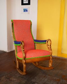 a wooden rocking chair sitting on top of a hard wood floor next to a yellow wall