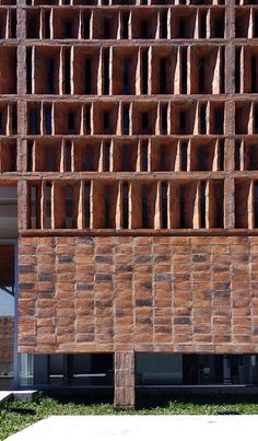 the side of a brick building with lots of windows on it's sides and grass in front of it