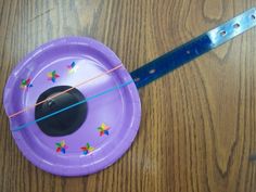 a purple frisbee with colorful stars on it sitting on a wooden table next to a knife