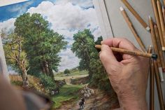 a person is drawing with colored pencils in front of some trees and other things