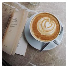 a cappuccino on a saucer next to a book