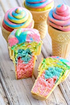 three ice cream cones with different colored frosting on them and one has a bite taken out of it