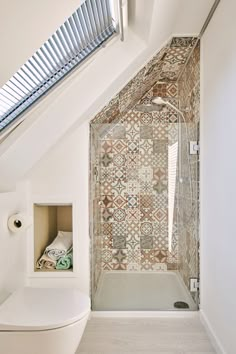 a bathroom with a toilet, shower and tiled walls in it's attic space