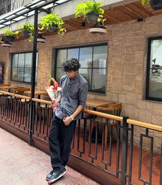 a man standing on a sidewalk holding flowers