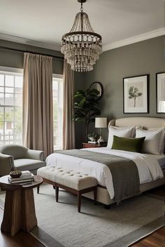 a bedroom with a large bed, chandelier and two chairs in front of the window