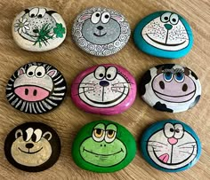 six painted rocks with different faces on them sitting on a wooden surface, each depicting an animal's face