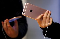 a person holding an iphone up to their face with ear buds in front of them