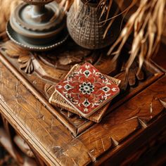 a red and black flowered plate sitting on top of a wooden table next to a lamp