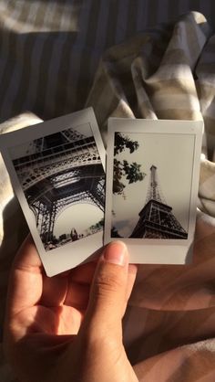 two polaroid photos in the palm of someone's hand, with the eiffel tower in the background