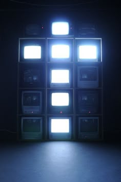 an empty room with several televisions and lights on the wall in front of it