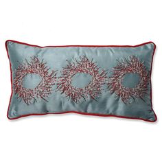 a blue pillow with red trim and two wreaths on it