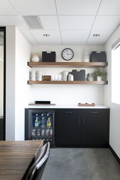 a kitchen area with shelves, cabinets and a clock on the wall