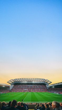 a large stadium filled with lots of people sitting on the bleachers at sunset